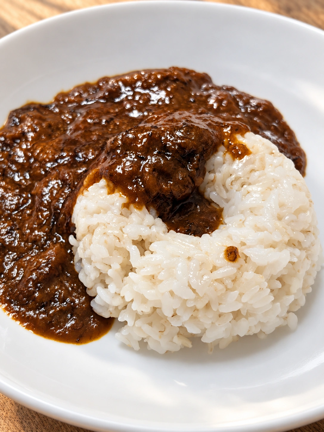 白い皿に盛ったレトルトカレーとライス（卓上・光・細部をAIで加工）